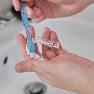 Patient cleaning clear aligner in sink