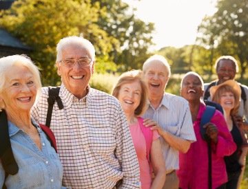 Group of older adults outside together hiking and laughing